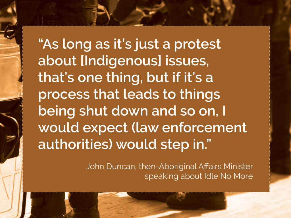 Quote over an image of riot gear standing in a row, facing away from the camera. The quote reads" “As long as it’s just a protest about [Indigenous] issues,  that’s one thing, but if it’s a process that leads to things being shut down and so on, I would expect (law enforcement authorities) would step in.”  It is from John Duncan, then-Aboriginal Affairs Minister speaking about Idle No More.