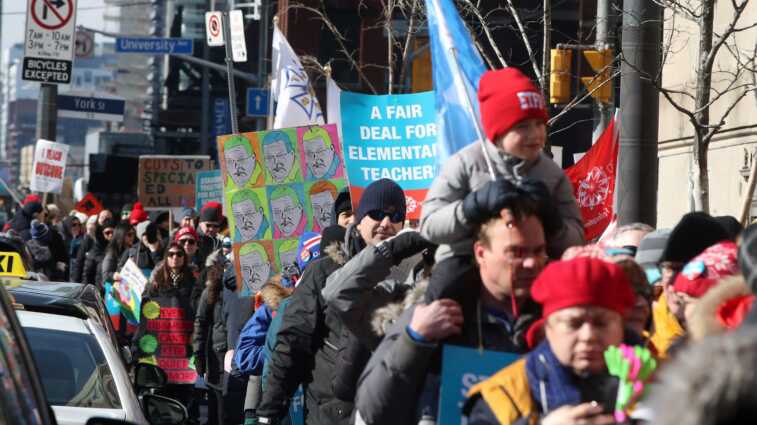 Teachers march, chant and sing crowding the sidewalk outside the Royal York as Education Minister Stephen Lecce speaks to the Canadian Club