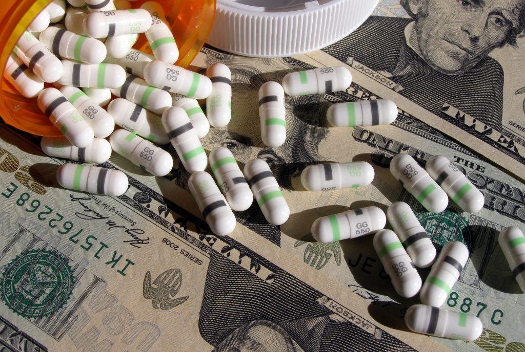 Photo of prescription drugs spilled onto a stack of U.S. currency.